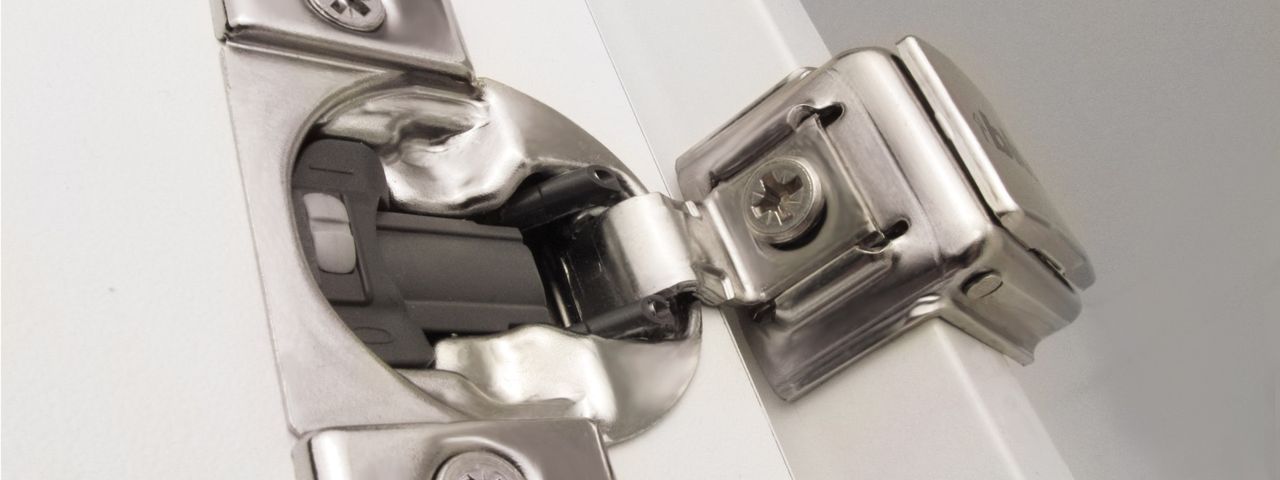 Close-up of a concealed soft-close hinge on a white cabinet door